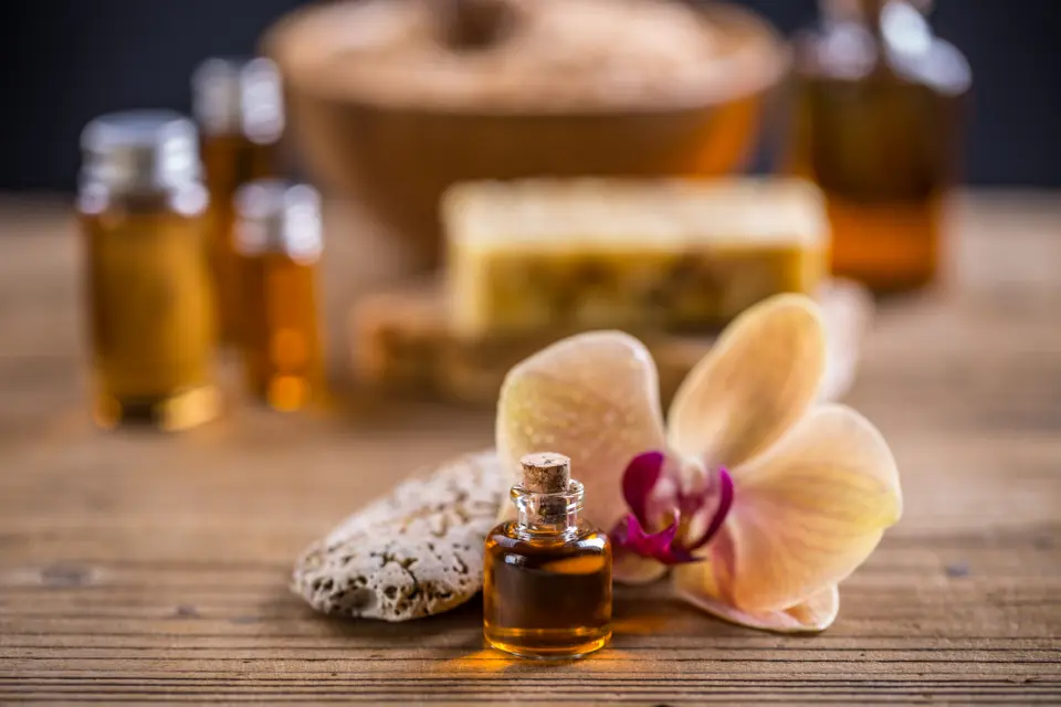 Bottles of massage oil, a pumice stone and an orchid bloom on a wooden table